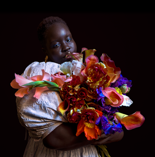 Billede taget i svagt lys af en person, der holder en farverig blomsterbuket.