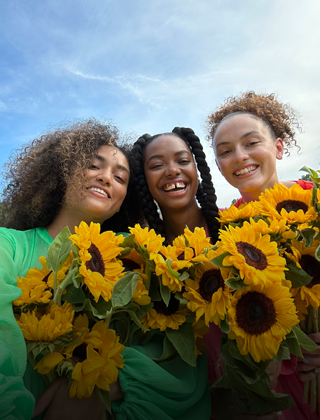 En skarp og levende selfie af tre personer med blomster i hænderne.