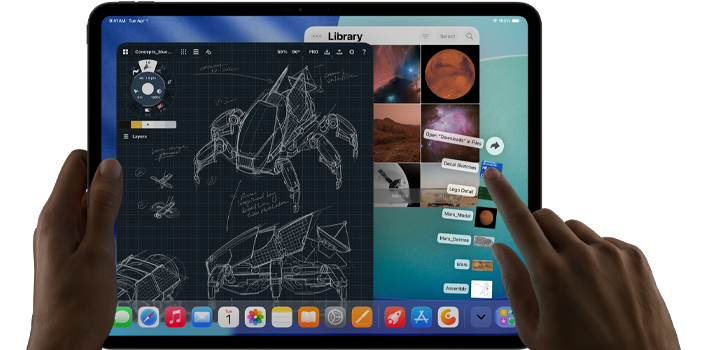 En venstre hånd holder en iPad Pro i fargen stellarsvart, mens en høyre hånd bruker en håndbevegelse for å navigere i flere åpne appvinduer, blant annet en tegneapp med skisser av mekaniske designer og et bildebibliotek med bilder av planeter og verdensrommet. Nedlastinger-mappen vises som et vifteformet overlegg.