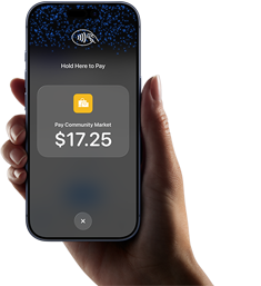 En persons højre hånd holder en iPhone, hvor skærmen viser et bestemt beløb, der skal betales, samt instruktioner til at foretage kontaktløs betaling, når brugeren er klar