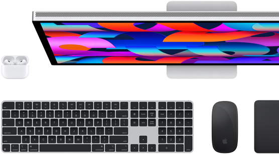 Billede ovenfra af en Studio Display-skærm, et sort Magic Keyboard, en sort Magic Mouse, en sort Magic Trackpad og et hvidt AirPods-etui