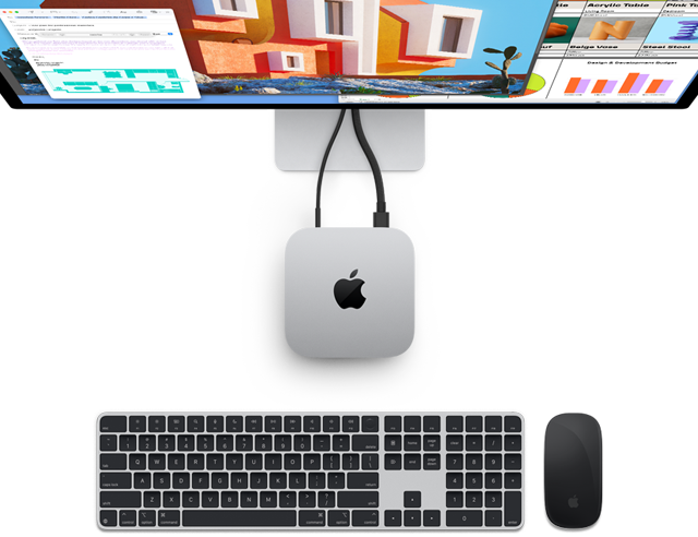 Hopeanvärisen Mac minin yläosa, jossa Apple-logo, kuvassa näkyy, miten Mac miniin on liitetty näyttö. Vieressä ovat langattomat Magic Keyboard ja Magic Mouse