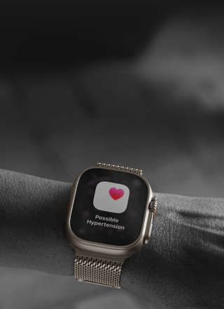 En person bærer en Apple Watch Ultra 3 på håndleddet. På skjermen vises det et helsevarsel om mulig høyt blodtrykk.