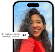 Voiceover på iPhone 15 beskriver en bild med orden en skrattande person med vågigt svart hår