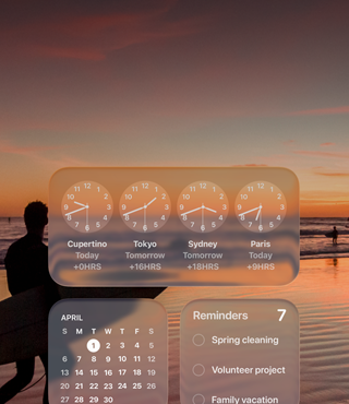 Liquid Glass-widgeter for Klokke, Kalender, Påminnelser og Været på en macOS Tahoe-skjerm over et bilde av en surfer som går på en strand i solnedgang