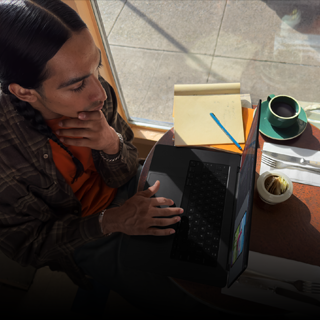 En person i en kafé jobber på en MacBook Pro som ikke er koblet til strøm