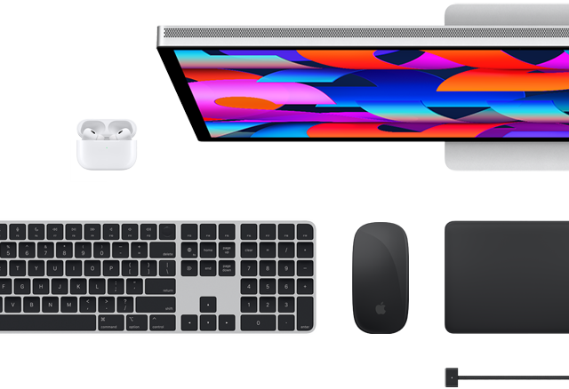 Mac-tilbehør vist ovenfra: Studio Display, Magic Keyboard, Magic Mouse, Magic Trackpad, AirPods og MagSafe-ladekabel
